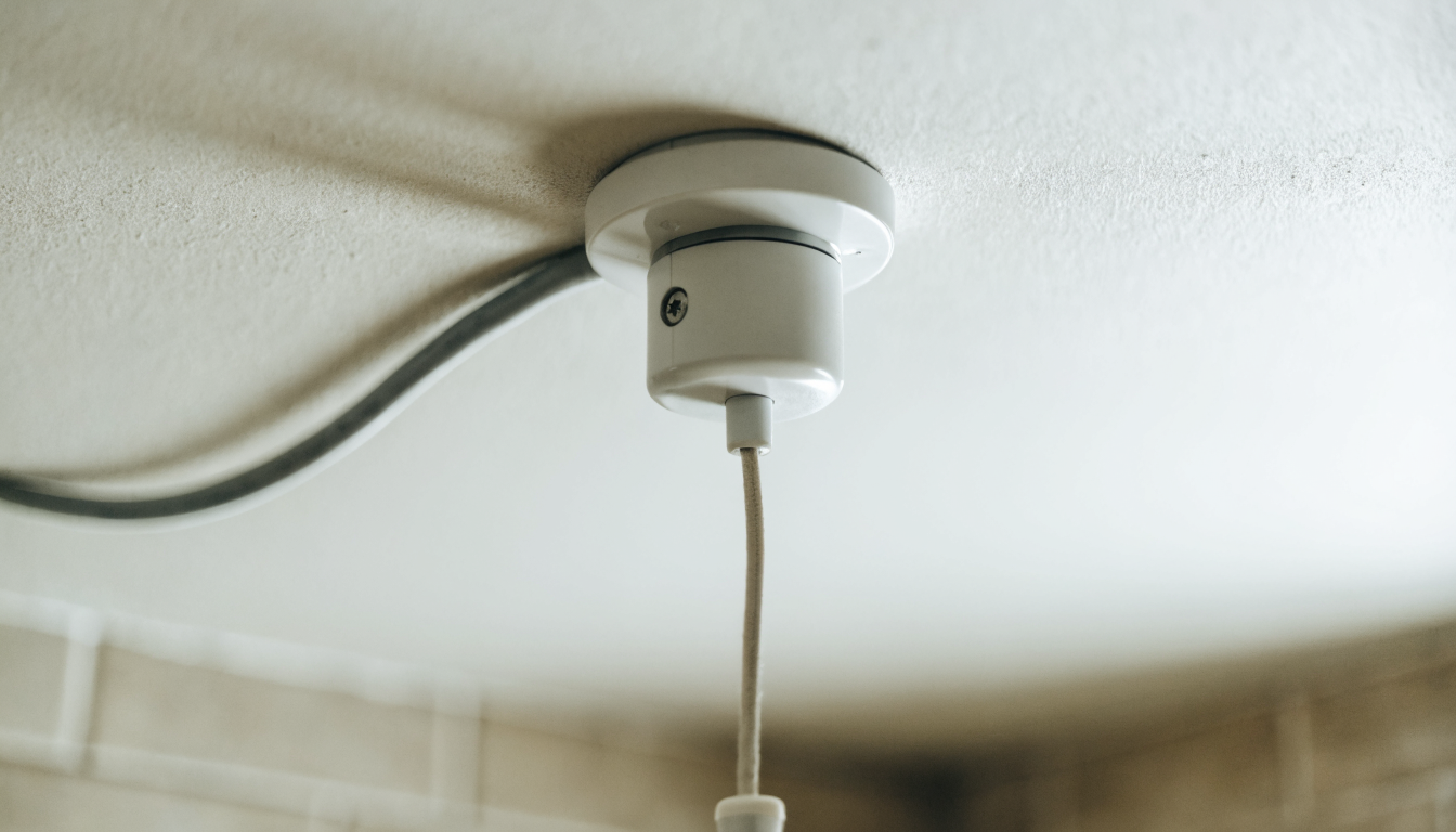 A ceiling mounted pull cord isolator switch above a bathroom door, the type used to isolate an electric shower